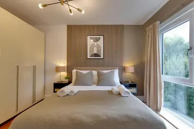 a bedroom with a large bed with a large window at Pass the Keys Stylish Riverside Apartment with Free Parking in Cambridge