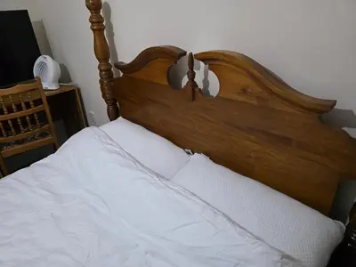 a bed with a wooden headboard and white sheets at Colchester Central and calm Ni in Hythe