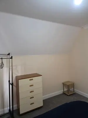 a bedroom with a white wall and a dresser at Colchester Central and calm Ni in Hythe