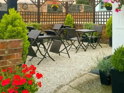 a patio with tables and chairs and red flowers at Guest Rooms at The Green Man in Takeley