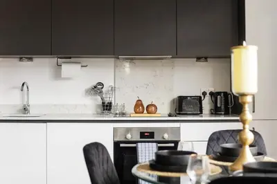 a kitchen with black cabinets and a table with chairs at Stonebridge House Apartment in Chelmsford