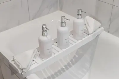 four white bottles sitting on a shelf in a bathroom at Stonebridge House Apartment in Chelmsford