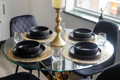 a glass table with black plates and hats on it at Stonebridge House Apartment in Chelmsford
