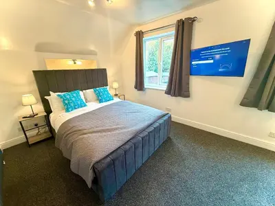 a bedroom with a bed with blue pillows and a window at Coastal Lodge in Leiston
