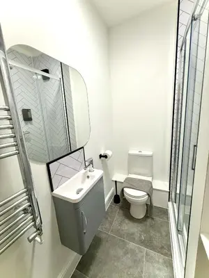 a white bathroom with a toilet and a sink at Coastal Lodge in Leiston