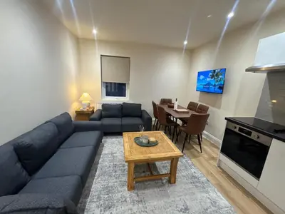 a living room with a blue couch and a table at Bright & Stylish 3-Bedroom Flat in Ipswich