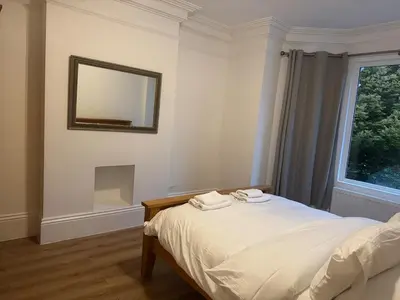 a bedroom with a bed with a mirror and a window at Bright & Stylish 3-Bedroom Flat in Ipswich
