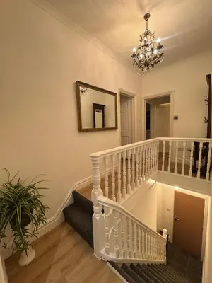 a white staircase in a living room with a chandelier at Bright & Stylish 3-Bedroom Flat in Ipswich