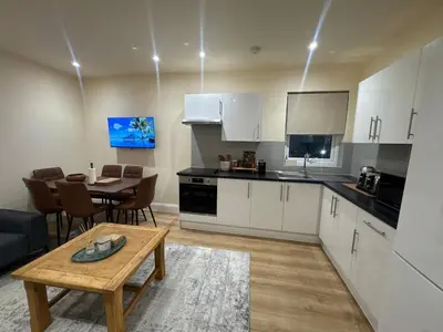 a kitchen with white cabinets and a table and a dining room at Bright & Stylish 3-Bedroom Flat in Ipswich