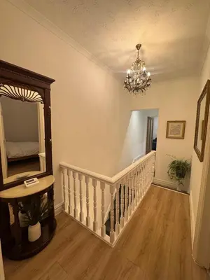 a hallway with a staircase with a mirror and a chandelier at Bright & Stylish 3-Bedroom Flat in Ipswich