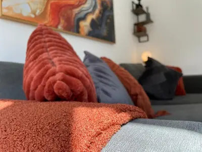 a red blanket sitting on top of a couch with pillows at Iris Cottage 4BR Coastal Retreat in Wenhaston