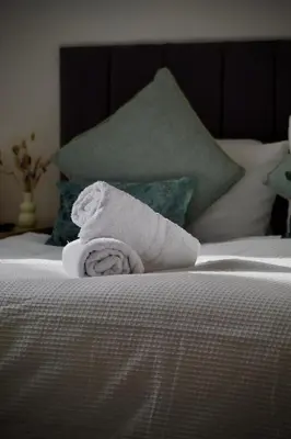 a white towel sitting on top of a bed at Iris Cottage 4BR Coastal Retreat in Wenhaston
