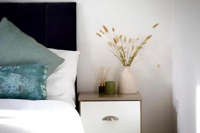 a bed with a night stand with a vase on it at Iris Cottage 4BR Coastal Retreat in Wenhaston