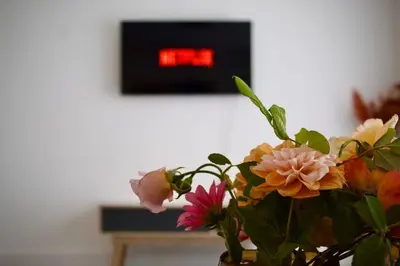 a vase filled with flowers in front of a clock at Iris Cottage 4BR Coastal Retreat in Wenhaston