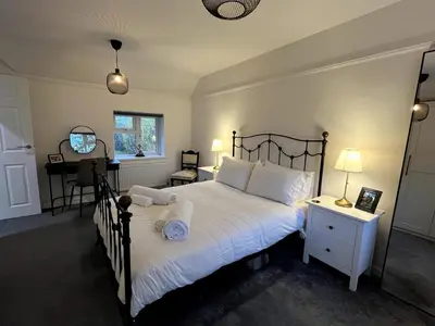 a bedroom with a bed with white sheets and a desk at Cottage Stay in Hingham in Hingham