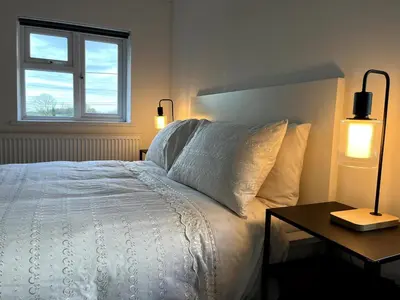 a bedroom with a white bed with a table and two lights at Cottage Stay in Hingham in Hingham