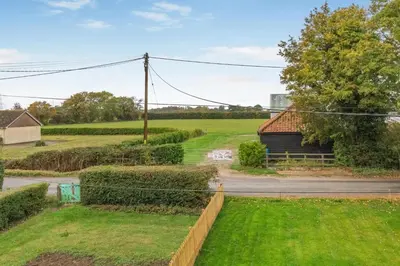 a view of a field with a house and a road at 2 Bed in Knodishall oc-s33543 in Friston