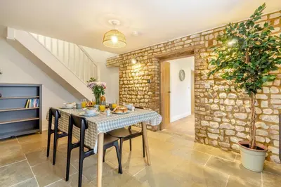 a dining room with a table with chairs and a stone wall at 2 Bed in Fincham oc-t33561 in Fincham