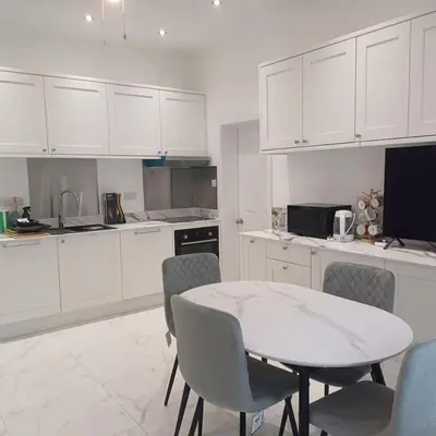 a kitchen with white cabinets and a table and chairs at Newly refurbed 3Bed Annexe - With Parking! in Albury