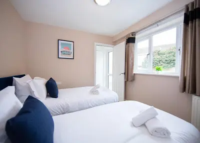 two beds in a room with a window at Stylish central location 3 bedroom house in Ely