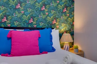 a bedroom with a bed with blue and pink pillows at Pass the Keys Ground Floor Apartment with Free Parking in Cambridge