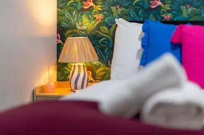 a bed with a table with a lamp on it at Pass the Keys Ground Floor Apartment with Free Parking in Cambridge