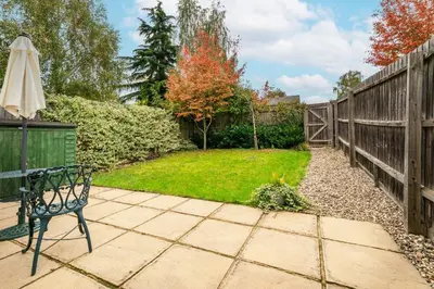 a patio with a bench and an umbrella at Chic 3Bed House & Garden Near Shelford High Street in Trumpington