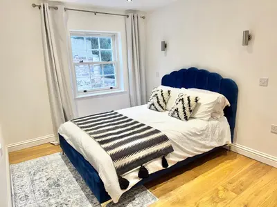a bed with a blue headboard in a room at 4 bed Townhouse in Central Bury St Edmunds in Bury Saint Edmunds
