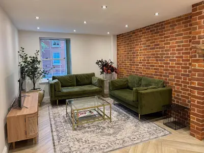 a living room with two green couches and a brick wall at 4 bed Townhouse in Central Bury St Edmunds in Bury Saint Edmunds
