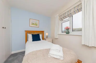 a bedroom with a large bed and a window at Top Step Cottage in Aldeburgh