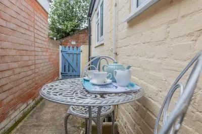 a table with two chairs and two cups on it at Top Step Cottage in Aldeburgh