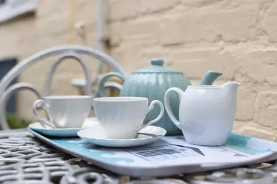 a tray with cups and saucers on a table at Top Step Cottage in Aldeburgh