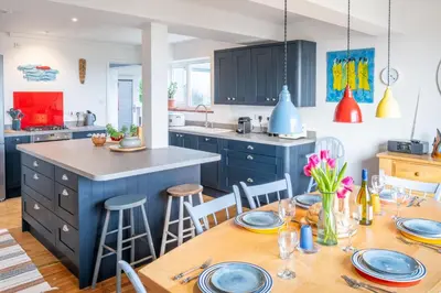 a kitchen with blue cabinets and a wooden table at Chicoutimi 4 in Thorpeness