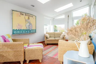 a living room with wicker chairs and a table at Chicoutimi 4 in Thorpeness