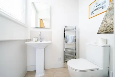 a white bathroom with a toilet and a sink at Chicoutimi 4 in Thorpeness