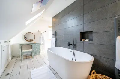 a bathroom with a white tub and a gray wall at Chicoutimi 4 in Thorpeness