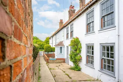 a row of white houses next to a brick wall at Sanderlings 4 in Aldeburgh