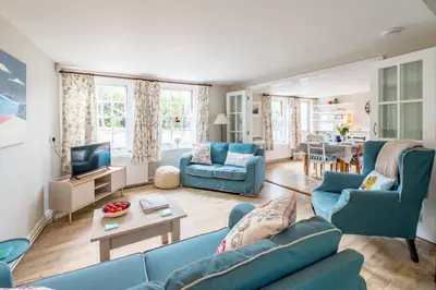 a living room with blue couches and a tv at Sanderlings 4 in Aldeburgh