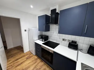 a kitchen with blue cabinets and a white refrigerator at Cosy Apartment in Chelmsford City, Free WiFi & Free Parking - Durrant Apartment by Stays Accommodation - Long Stays Welcome in Chelmsford