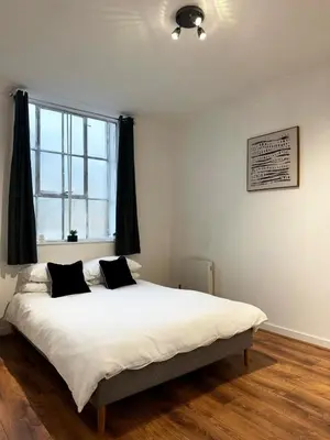 a bedroom with a large white bed with black pillows at Cosy Apartment in Chelmsford City, Free WiFi & Free Parking - Durrant Apartment by Stays Accommodation - Long Stays Welcome in Chelmsford