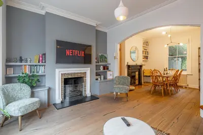 a living room with a fireplace and a table and chairs at Stylish Victorian Home Nr Cambridge Station in Cambridge