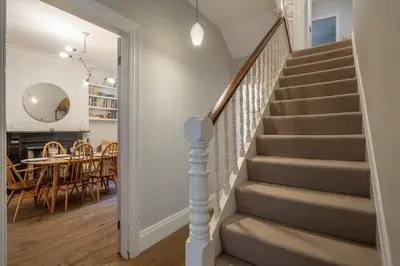 a staircase in a home with a dining room and a table at Stylish Victorian Home Nr Cambridge Station in Cambridge