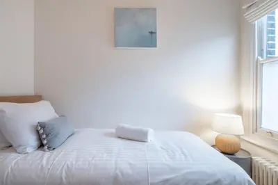 a white bed in a room with a window at Stylish Victorian Home Nr Cambridge Station in Cambridge
