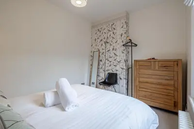 a bedroom with a white bed and a wooden dresser at Stylish Victorian Home Nr Cambridge Station in Cambridge