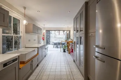 a kitchen with white cabinets and a white tile floor at Stylish Victorian Home Nr Cambridge Station in Cambridge