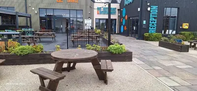 a wooden table and benches in front of a building at Heavenly Huts GC056 in Saint Osyth