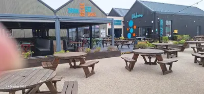 a group of picnic tables and benches in front of a restaurant at Heavenly Huts GC056 in Saint Osyth
