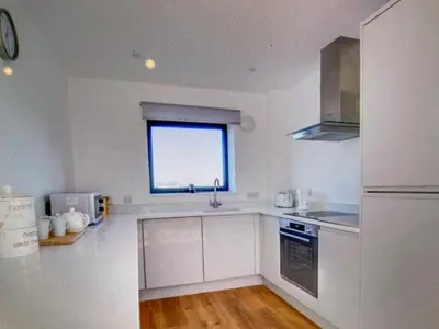 a kitchen with white cabinets and a window at Admirals in Shotley Gate