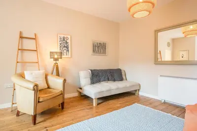 a living room with a chair and a mirror at Suffolk House, Saxmundham in Saxmundham