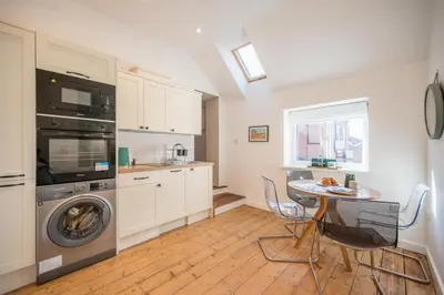 a kitchen with a washing machine and a table with chairs at Suffolk House, Saxmundham in Saxmundham